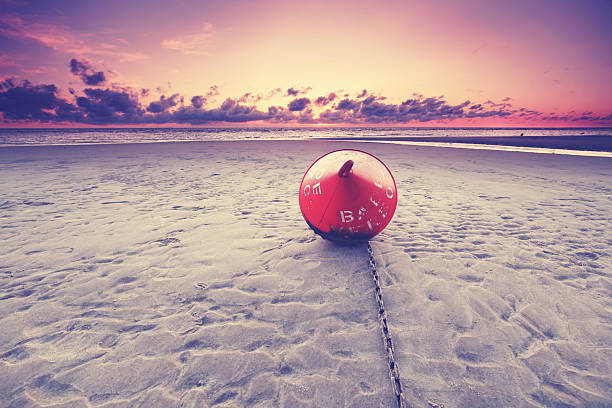 sunset at the beach - orange buoy in the sand
