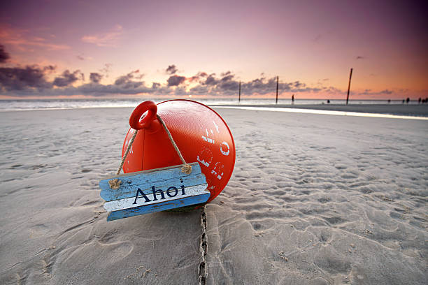 Sunset Sentinel: Weathered Orange Buoy Resting on Sandy Shores
