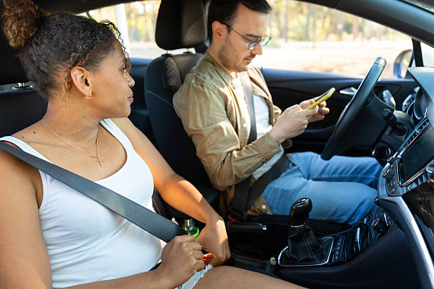 istock Woman fastening seatbelt while man using smartphone while driving 2219260960
