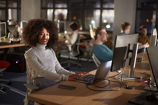 istock Happy black female programmer working on computers late in the office. 2219262411