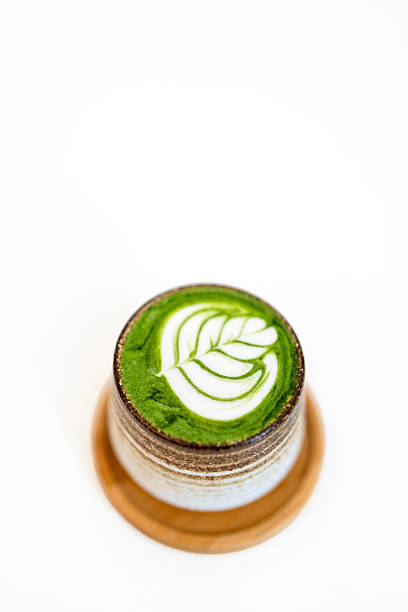 Matcha latte with leaf art in ceramic cup on white background
