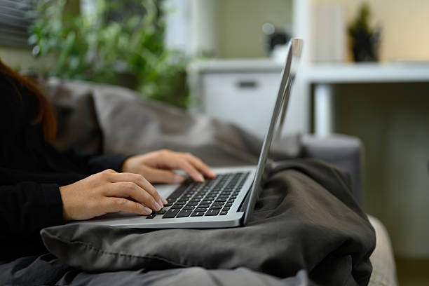 istock Side view of freelancer types on a laptop while resting on a sofa 2219276773