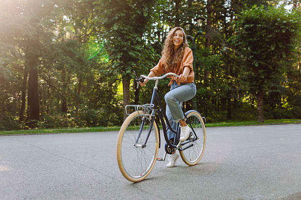 istock Young woman riding a bicycle in a green park. 2219277720