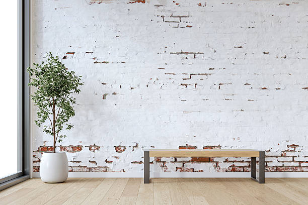 istock A minimalistic interior with a wooden bench and potted plant in front of an empty ruined white brick wall background with copy space, window and decoration 2219279708