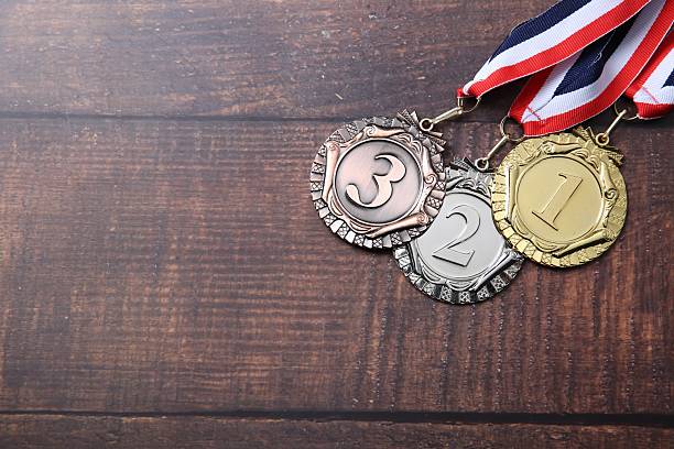 Golden, silver and bronze medals on wooden background, top view. Space for text
