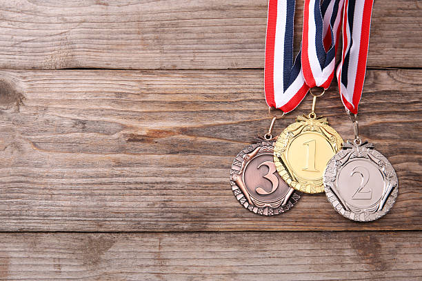Golden, silver and bronze medals on wooden background, top view. Space for text