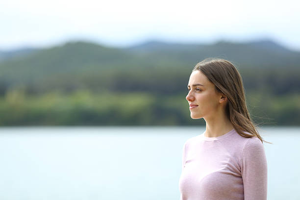 Portrait of a confident woman standing alone looking away in nature