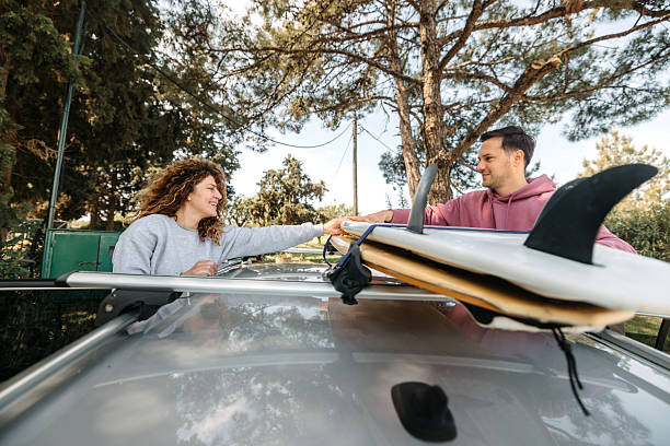 istock Young smiling couple loading surfboards on car rooftop together 2219285374