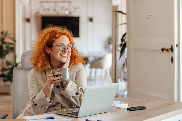 istock Smiling Professional Drinking Coffee While Working on a Laptop in Office 2219286677