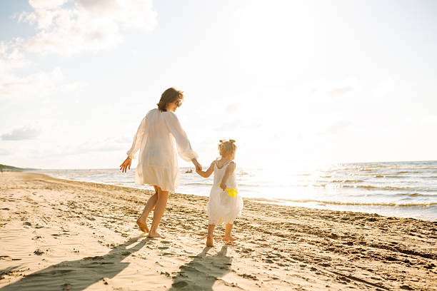 istock Happy mother and daughter strolling together on a sunny beach. 2219289216