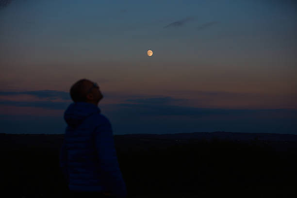istock Silhouette of a man observing Moon, Milky Way stars, planets and other celestial objects from a dark countryside location. 2219289665