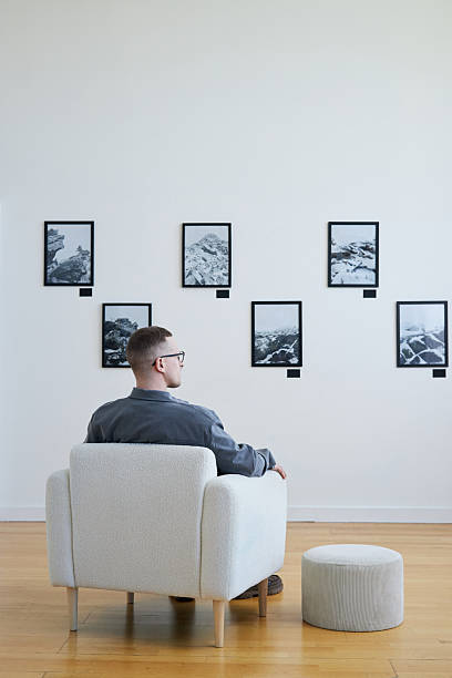 istock Man Observing Gallery Wall with Framed Photos 2219291758