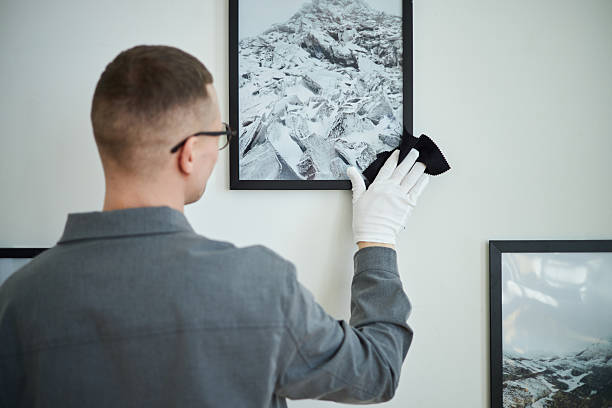 istock Cleaning Framed Picture on Wall with Gloved Hand 2219291820