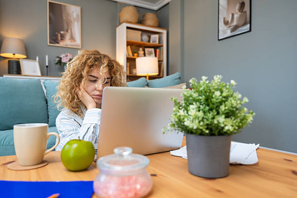 istock Young woman struggling with focus while working on laptop on floor, surrounded by printed analytic, battling ADHD, mental fatigue, burnout, and the pressure of modern multitasking expectations 2219293248