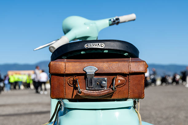 Reggio Calabria - Kalabrien - 05-18-2025: Leather suitcase strapped to a mint-green vintage scooter at the Distinguished Gentlemans Ride in Reggio Calabria, seen from behind.