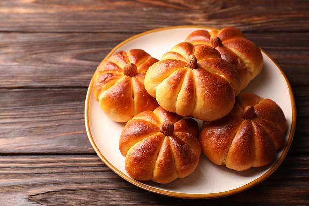 istock Tasty pumpkin shaped buns on wooden table, closeup 2219295279