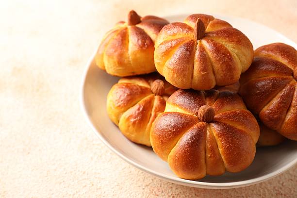 istock Tasty pumpkin shaped buns on beige textured table, closeup 2219295367