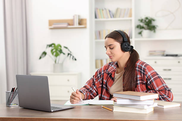 istock Student in headphones studying at wooden table indoors 2219296762