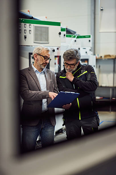 istock Two Professionals Collaborating in an Industrial Setting Discussing Equipment 2219297104