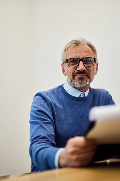 istock Professional Man in Office Wearing Glasses and Sweater Assisting with Paperwork 2219297139