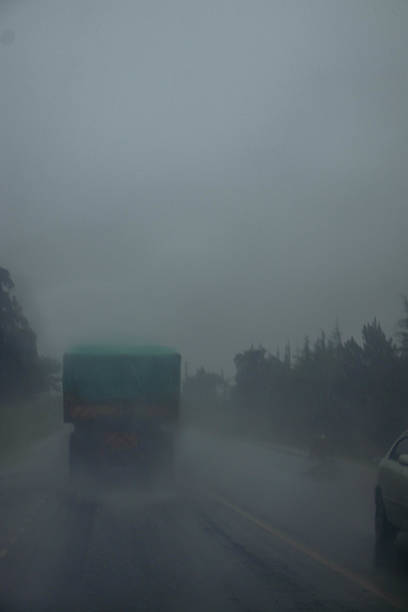 A behind view of a truck driving  on a highway during a heavy down pour.