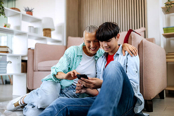 istock Mother and son using smartphone while relaxing on the floor at home 2219298519