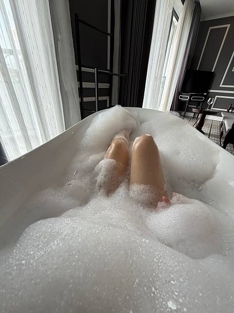 istock vertical photo Bubble bath relaxation young woman taking bubble bath at home 2219299066
