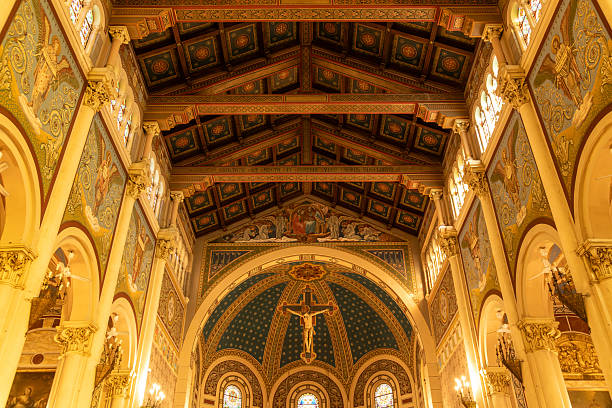 Reggio Calabria - Kalabrien - 05-22-2025: Decorated ceiling with religious motifs, crucifix, and mosaics, flanked by colorful stained glass and arched upper wall murals