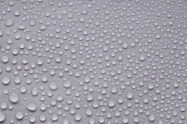 Close-up of water droplets on light blue glass surface forming clean abstract background texture, Horizontal.