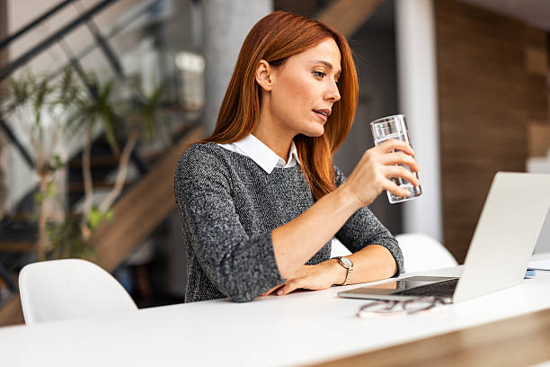 istock Professional Woman Drinking Water While Working on Laptop in Modern Office 2219300906