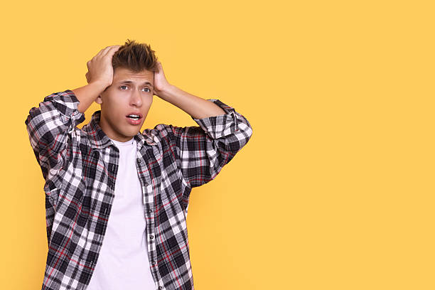 istock Stressful young student before exam on yellow background, space for text 2219302002