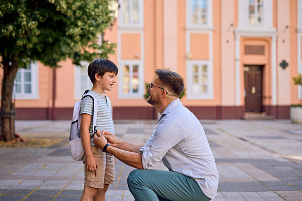 istock Father adjusting son's backpack before school in front of the school 2219302599