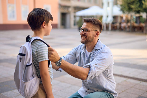 istock Father adjusting son's backpack before school in urban setting 2219302632