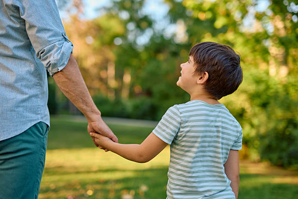 istock Father and son holding hands walking in a park looking up 2219302987
