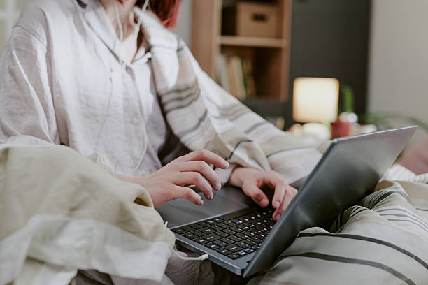 Woman Typing on Laptop While Sitting on Cozy Bed