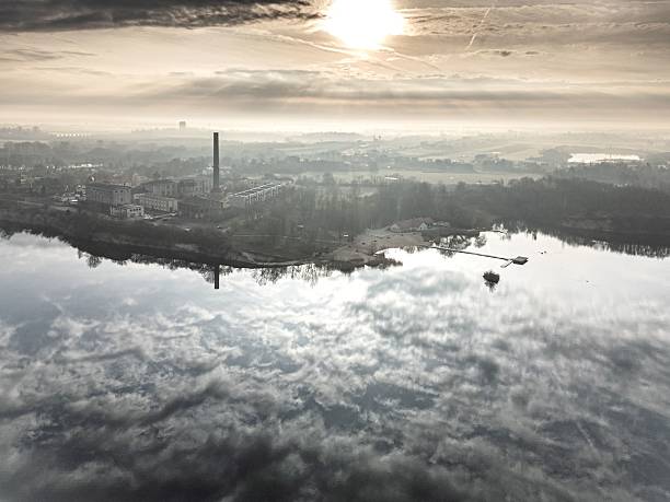 Aerial view of an industrial landscape with a river reflecting the cloudy sky at sunrise.