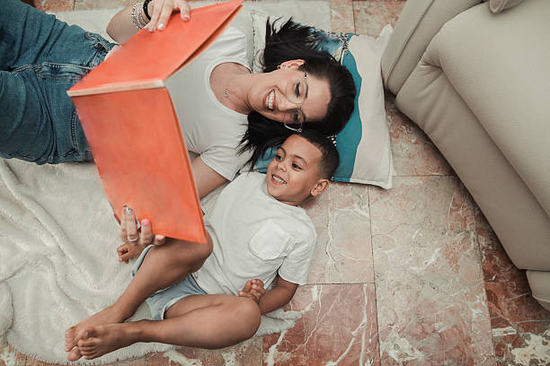 Mother and little son reading book together at home
