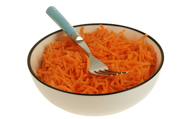 Plate of grated carrots with a fork close-up isolated on white background