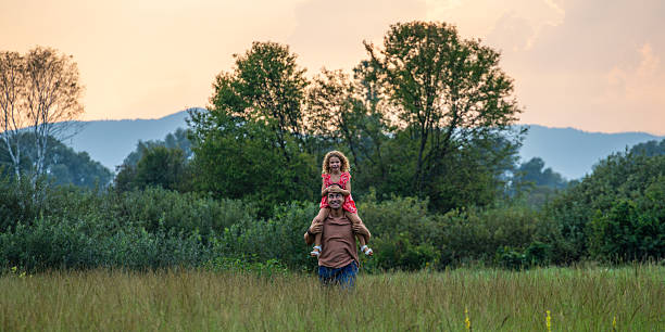 A father with her son on his shoulder in the forest.