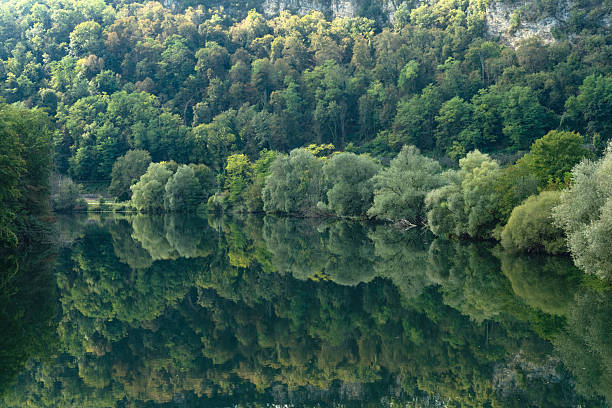 Beautiful green trees reflected in the River Doubs as it winds its way through the stunning landscape between the French cities of Dole and Besancon in Eastern France, Europe.