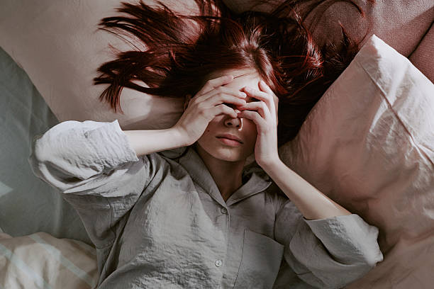 istock Woman Covering Face While Lying on Bed 2219316637