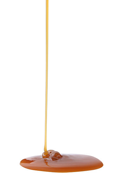 istock Tasty caramel sauce dripping on white background, closeup 2219321353