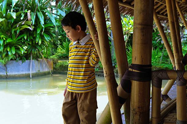 istock Thoughtful Child Standing Near Bamboo and Water 2219323118