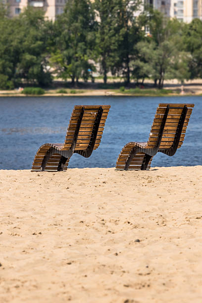 Wooden deck chair. Place on the beach. Summer vacation. City beach. Obolonsky island. Sandy beach. Rest on the Dnieper river. Introvert's paradise. Sunbathing in nature. Sun protection with SPF. Benefits and harm of ultraviolet. How to tan correctly. Skin cancer.