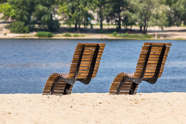 Two blue lounge chairs on the beach and a fisherman's boat on the sea.