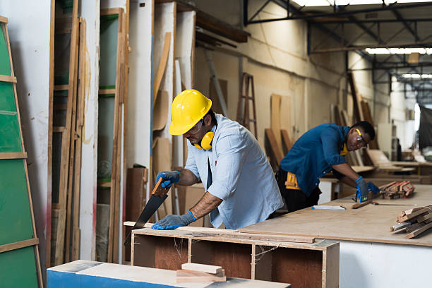 istock Carpenter, furniture workshop. Carpenter man using handsaw for cutting timber in carpenter wood factory 2219324200
