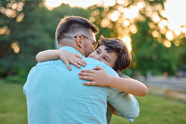 istock Father and son embracing in a park at sunset 2219324448