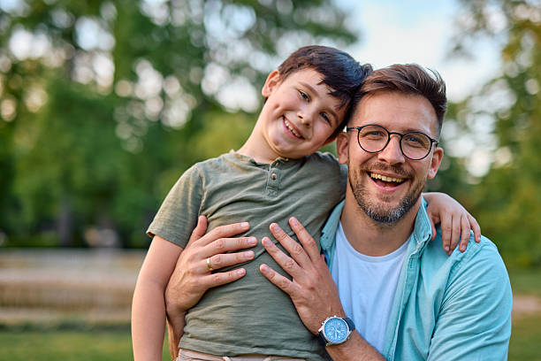 istock Happy father and son embracing and smiling at camera in a park 2219324496