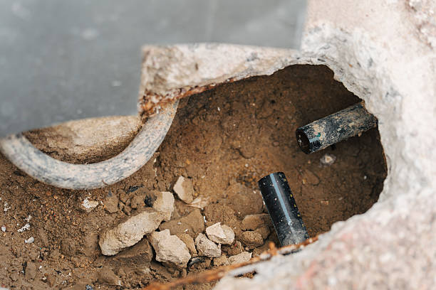 Ground excavation in progress for piping repair work. Construction site detail. Demolition work.