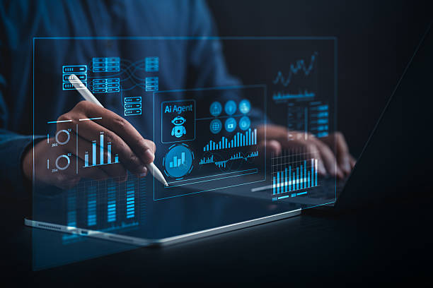 istock AI Business Analyst Collaborating with Virtual AI Agent to Analyze Big Data in Real Time on a Holographic Dashboard with Computers and Laptops in a Dark Blue-Lit Room 2219327897